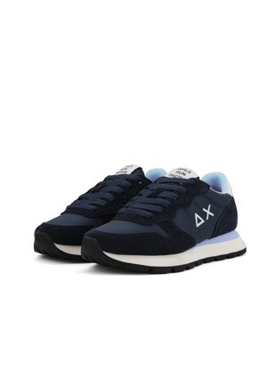Un paio di sneaker blu navy con suole bianche, lacci neri e testo "LE RAGAZZE CORRONO VELOCE" sulla linguetta, angolato su uno sfondo bianco.