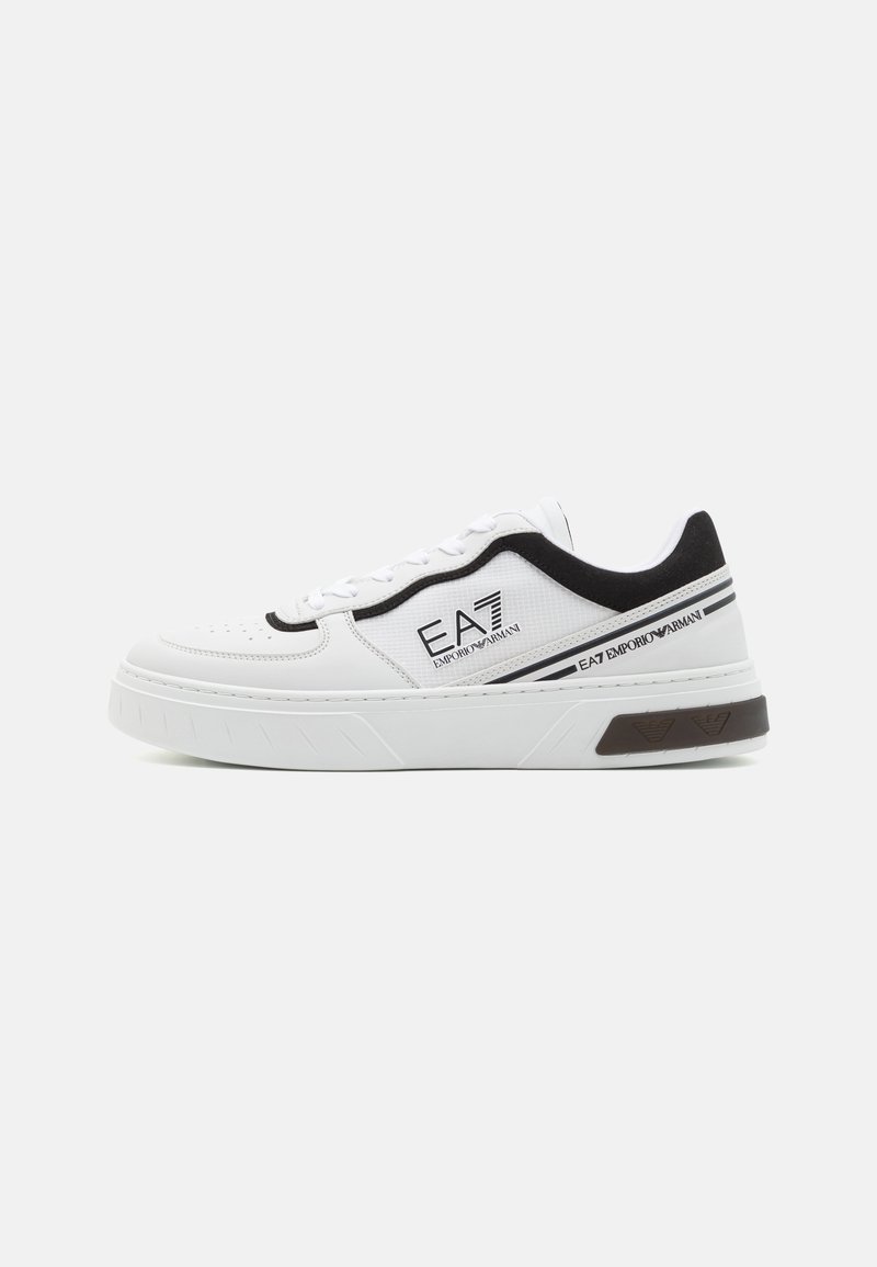 White sneakers with a textured leather upper, black accents, and a thick, ridged sole. Logo printed on the side; eyelets for laces.