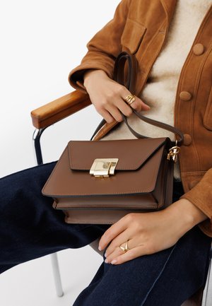 Bolso de mano de cuero marrón con herrajes dorados, forma rectangular y cierre de solapa. Cuenta con una correa desmontable y costuras contrastantes.