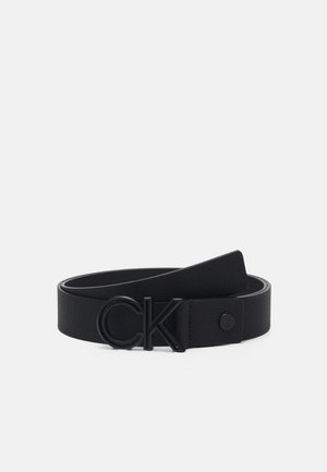 Cintura in pelle nera con finitura testurizzata, fibbia con logo "CK" nero ben visibile e cinturino liscio con chiusura a pressione.
