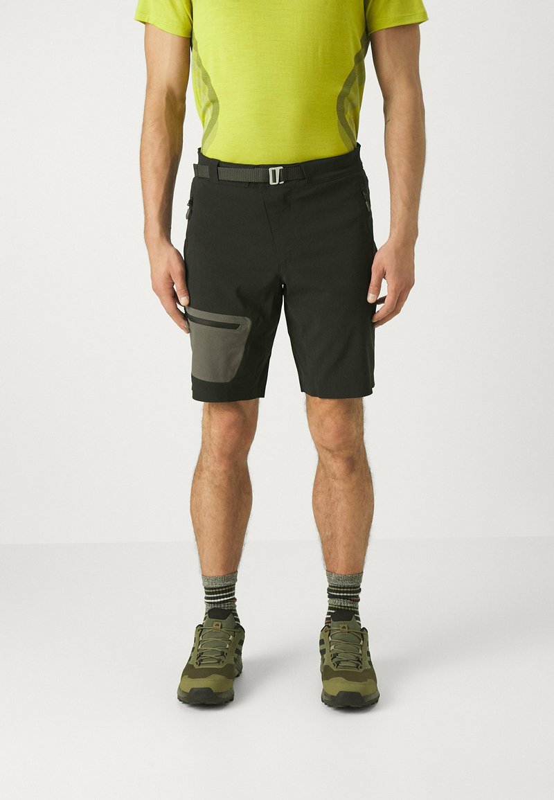 Shorts noirs avec une poche texturée grise foncée, une coupe respirante et une ceinture grise. Associés à des chaussures de randonnée vertes et des chaussettes rayées.