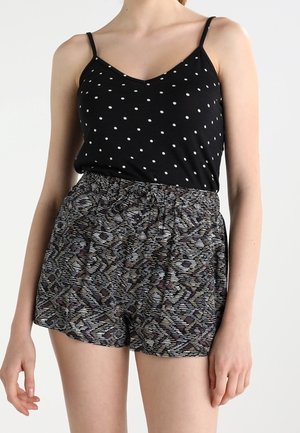 Zwarte tanktop met stippen en dunne bandjes, gecombineerd met loszittende, patroonshorts in grijs, paars en blauw. Elastische tailleband.