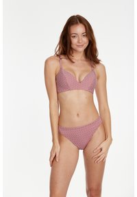 Crveni i bijeli geometrijski uzorak bikini set s dubokim izrezom i podesivim naramenicama, napravljen od glatkog, laganog materijala i s minimalnom pokrivenošću.