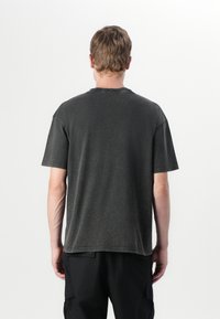T-shirt gris à manches courtes avec une coupe décontractée, présentant un col rond côtelé et un ourlet effiloché pour un look usé.