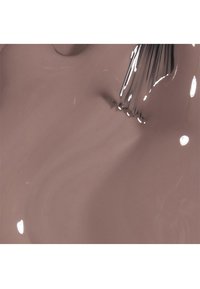 Nagellak in een crèmekleurige mauve tint, met een glanzende afwerking. Een kwast is gedeeltelijk zichtbaar, met fijne haren en een reflecterend oppervlak.