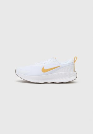 Bijela atletska cipela s prozračnom mrežicom, žutim Nike swoosh-om, teksturiranim petom i gumiranim potplatom. Dizajnirana za udobnost i potporu.