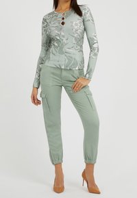 Haut à manches longues vert menthe avec motif floral et fermeture à quatre boutons, associé à un pantalon cargo assorti avec poignets élastiques et poches latérales.