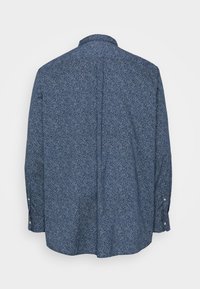 Camicia a maniche lunghe di colore blu con un piccolo motivo floreale bianco, colletto standard e polsini con bottone. Tessuto resistente con una trama liscia.
