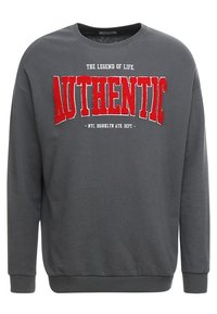 Tmavě šedá mikina s červeným texturovaným nápisem "AUTHENTIC" a menším bílým textem nad a pod nápisem na hrudi.