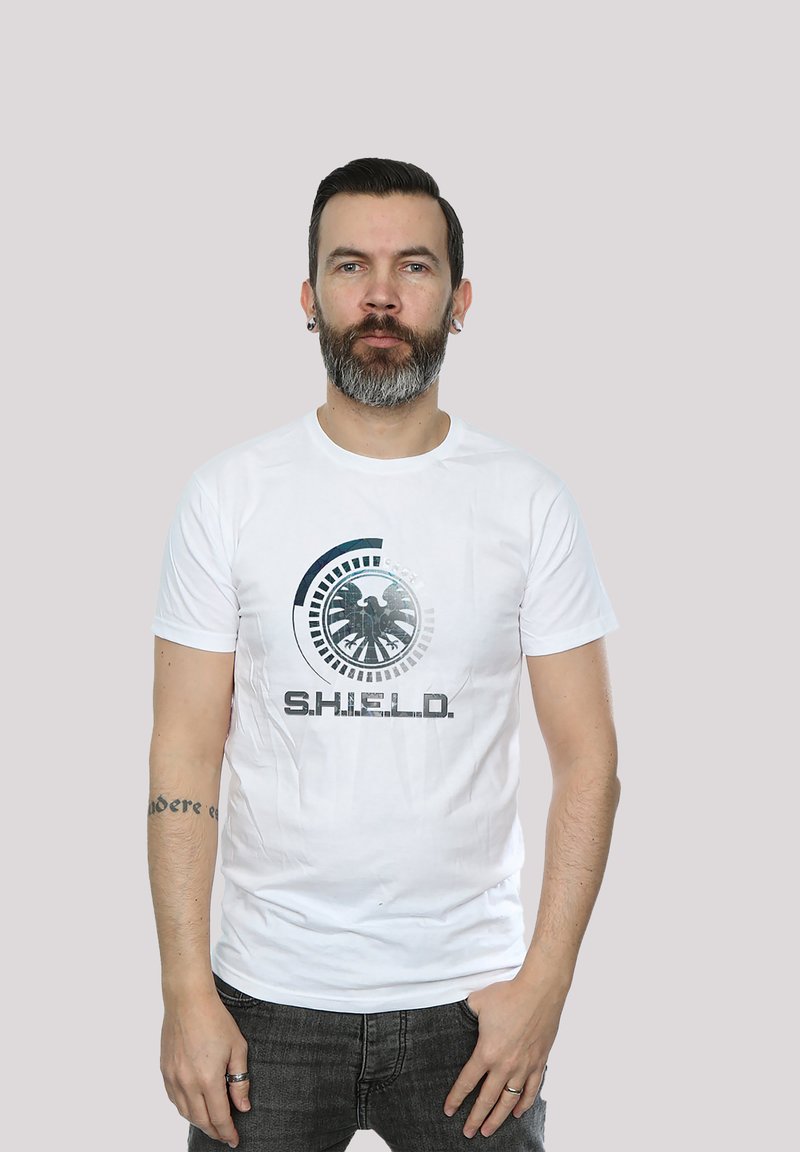 Hvit bomull t-skjorte med S.H.I.E.L.D. logo i svart og grått, kort ermer og rund halsdesign. Enkelt, avslappet snitt.