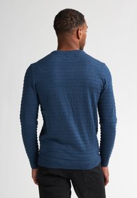 Pulover în dungi bleu marin, cu un design texturat, guler rotund și mâneci lungi, fabricat dintr-un material tricotat moale.