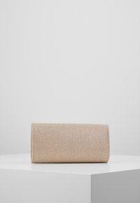 Béžová texturovaná kabelka typu clutch s válcovým tvarem a lesklým povrchem, obsahující jedno oddělení a žádné viditelné kovové součásti.