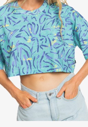 T-shirt court turquoise avec motifs abstraits violets et jaunes, col rond et manches courtes, assorti à un short taille haute en denim clair.