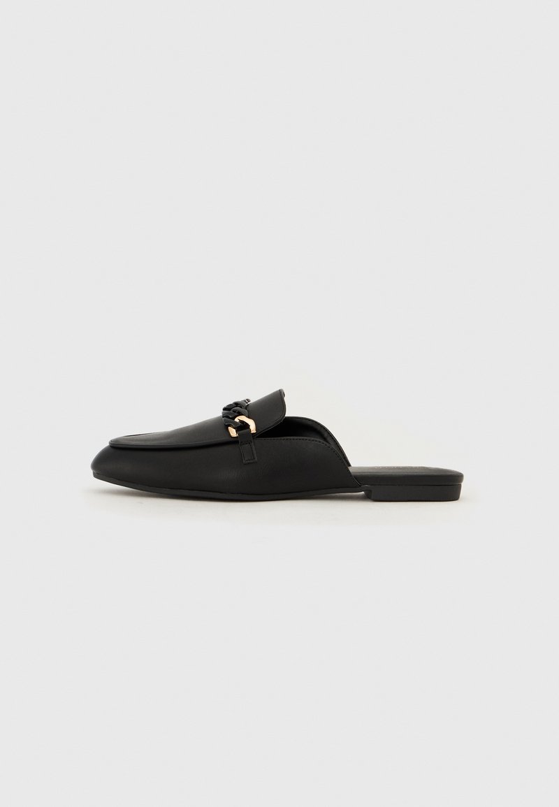 Black slip-on shoe made of smooth leather. Features a rounded toe, a decorative woven strap, and a small gold accent. Flat sole.