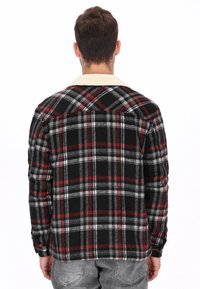 Camisa de franela a cuadros en negro y rojo con cuello sherpa beige, mangas largas y diseño de espalda con botones. Textura suave y tela duradera.