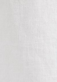 Texture de tissu blanc tissé avec un motif visible en forme de grille de fils entrelacés.
