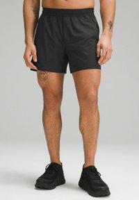 Black athletic shorts made of lightweight fabric, featuring an elastic waistband and smooth texture, paired with black sneakers.
