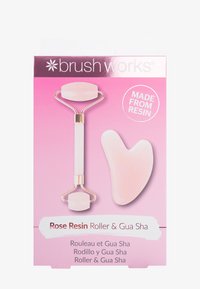 Rosa resinrulle och gua sha-set. Har en ljusrosa färg, slät yta, guldaccenter och ett hjärtformat gua sha-verktyg.