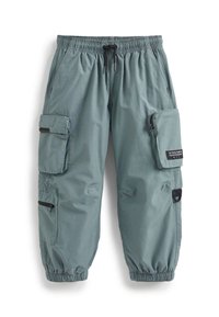 Pantalons cargo en tissu bleu clair-gris avec une taille élastique et un cordon de serrage. Dotés de multiples poches et fermetures éclair pour le rangement.
