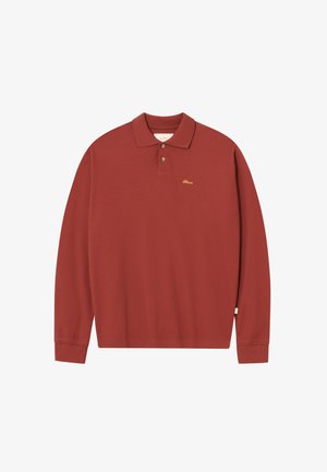 Rustfarvet langærmet polo skjorte med to knapper, ribbestruktur og lille gul broderet logo på venstre bryst.