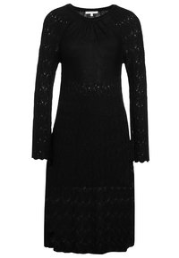 Abito nero a maglia con maniche lunghe, caratterizzato da un motivo testurizzato e un collo rotondo. Cade sotto le ginocchia. Materiale caldo e traspirante.