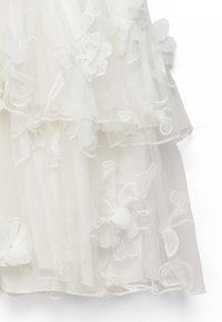 Hvidt gennemsigtigt stof med lagdelte flæser med broderede og applikationsblomster.