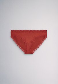 Røde dame-bikini-trusser med blonder, lagt fladt på en lysegrå baggrund.