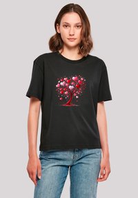 Black cotton t-shirt featuring a colorful tree design made of red and pink hearts, with a relaxed fit and crew neckline.