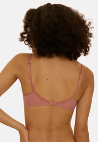 Soutien-gorge rose avec bretelles réglables, texture lisse et fermeture par agrafes à l'arrière. Design simple sans motifs ni ornements visibles.