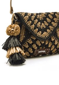 Gewebte Clutch aus Schwarz und Beige, mit einem Klappenverschluss, einem dekorativen Quastenanhänger mit geschichteten Texturen und einem Logoschild an der Seite.