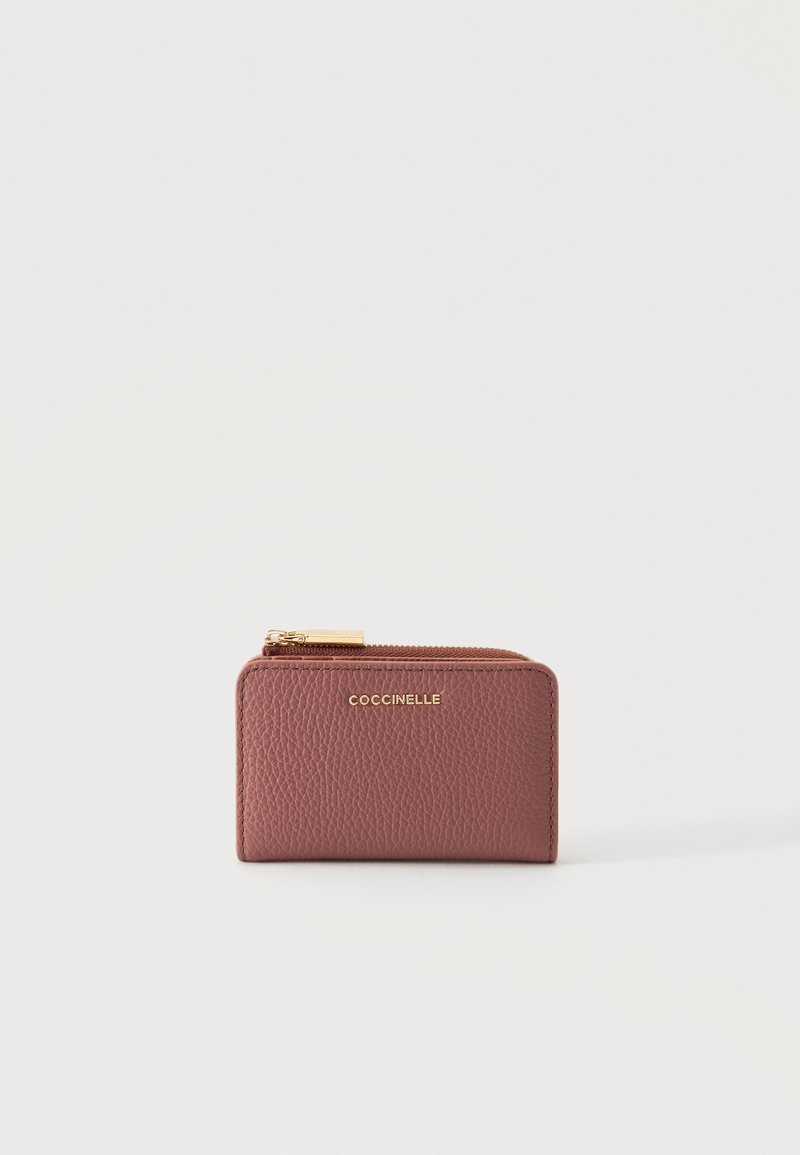Petit portefeuille zippé en cuir marron texturé avec fermeture éclair dorée et logo « Coccinelle » embossé sur le devant.