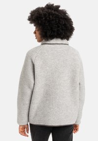 Gray fleece jacket with a textured surface, a high collar, and raglan sleeves, featuring a subtle contrasting trim along the neckline.