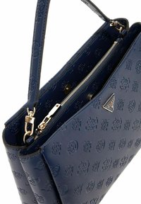 Donkerblauwe neplederen handtas met een geperforeerd logo-patroon, een ritsvak en een gouden hardware accent. Verstelbare schouderband inbegrepen.