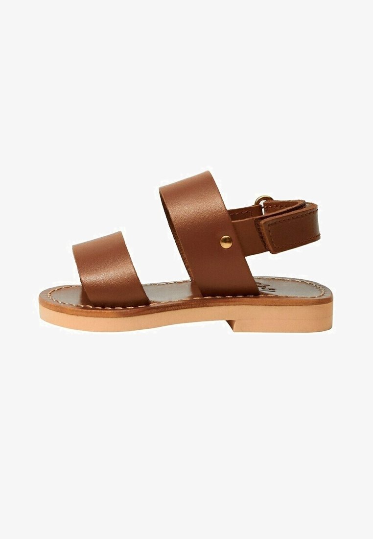 Brun læder flad sandal med to brede remme, en ankelrem med guldlås og en lysebrun sål med syninger rundt om kanterne.