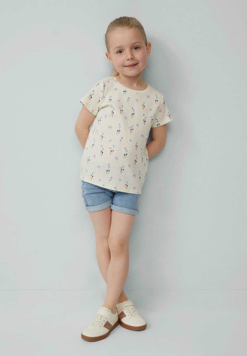 Lichtgekleurde geribde t-shirt met een bloemenpatroon, gecombineerd met denim shorts en crèmekleurige sneakers. Eenvoudig ontwerp, korte mouwen, losse pasvorm.