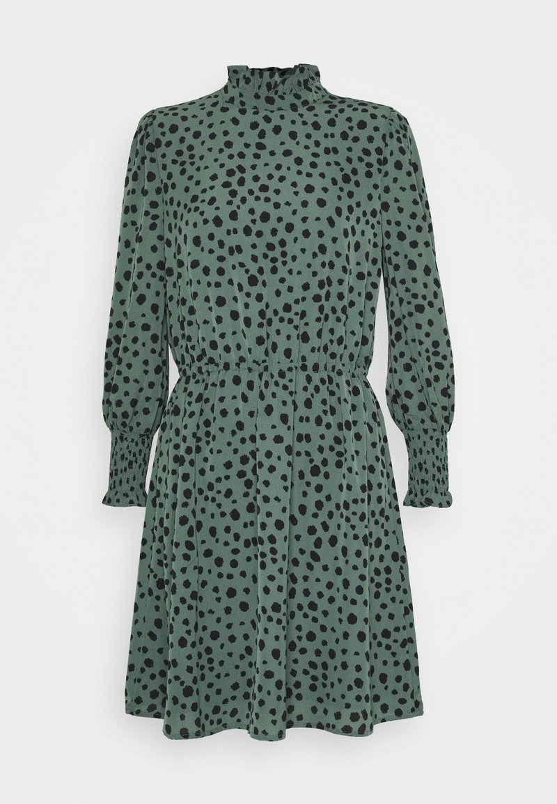 Robe verte à manches longues avec des taches noires irrégulières, col haut à volants, taille froncée et poignets smockés.