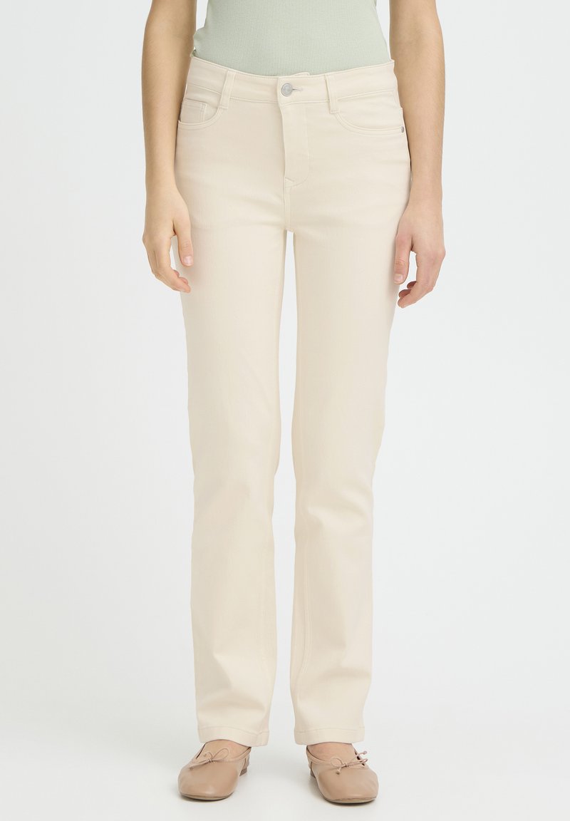 Beige lige bukser med fem lommer, knaplukning og en glat tekstur, kombineret med lysebrune ballerinaer.