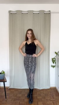 Μαύρη αμάνικη μπλούζα, πατινέ φούστα μίντι με μαυρόασπρη λεοπάρδαλη απόχρωση, συνδυασμένη με μαύρες μπότες μέχρι το γόνατο. Ουδέτερο φόντο με κουρτίνες.