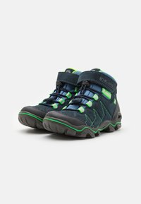 Chaussures de randonnée noires et bleues foncées avec des accents verts, présentant une semelle en caoutchouc robuste, un dessus en textile et des lacets cachés maintenus par une sangle en Velcro.