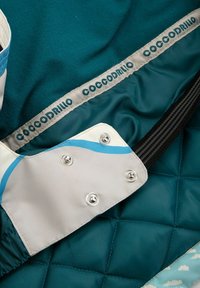 Pikowana tkanina w kolorze zielonkawo-niebieskim z szarymi i niebieskimi akcentami; wyposażona w zatrzaski i czarny elastyczny pasek; oznakowana marką "Coccodrillo" w zielonkawych literach.