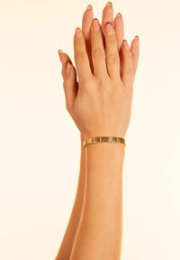 Guldmetallarmband med växlande platta och texturerade segment. Slät yta med en enkel, elegant design.