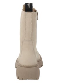 Botines beige con un acabado de cuero suave, que presentan un cierre de cremallera lateral, suela de goma gruesa y una tira negra en la parte posterior.