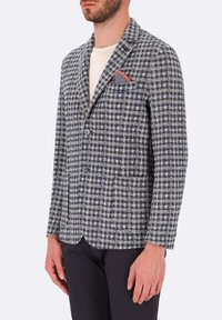Blazer a quadri navy e bianco realizzato in tessuto testurizzato, con due bottoni, rever a punta e fazzoletto da taschino con un accento arancione.