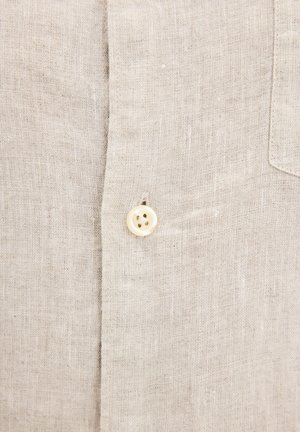 Camicia in lino beige con chiusura frontale a bottoni, dotata di un singolo bottone crema, tessuto testurizzato e taschino sul petto.
