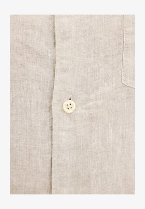 Beżowa lniana koszula z guzikowym zapięciem z przodu, z pojedynczym kremowym guzikiem, teksturowanym materiałem oraz naszywaną kieszenią na piersi.