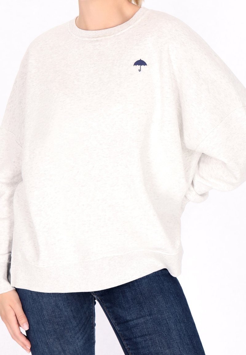 Vaaleanharmaa suurikokoinen huppari, joka on valmistettu pehmeästä materiaalista ja jossa on pieni tummansininen sateenvarjon brodeeraus rinnan kohdalla. Lörppö malli, jossa on joustavat hihansuut.