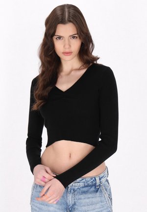 Top corto negro con rayas, de mangas largas y escote en V, que presenta un diseño ajustado que acentúa la cintura.