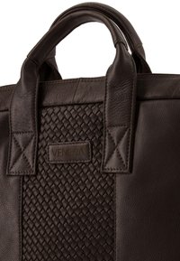 Brązowa skórzana torba o plecionej teksturze z przodu, z dwoma mocnymi uchwytami i prostokątnym kształtem. Na froncie widoczna jest metka z logo.