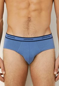 Modré pánské slipy s elastickým pasem, na kterém je nápis "yamamay" v námořnické modři. Materiál vypadá hladce a má těsný, přiléhavý střih.