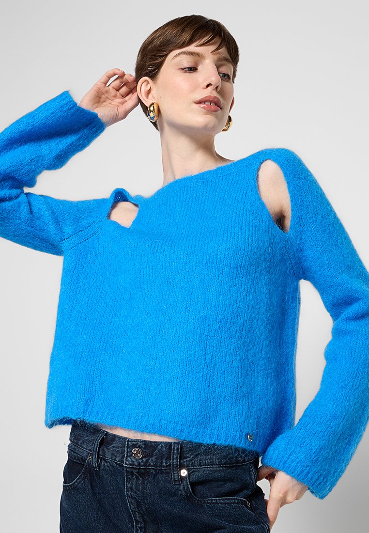 Maglione azzurro in maglia pelosa con maniche lunghe, caratterizzato da dettagli a taglio sulle spalle. Tessuto morbido e taglio rilassato, lunghezza crop.